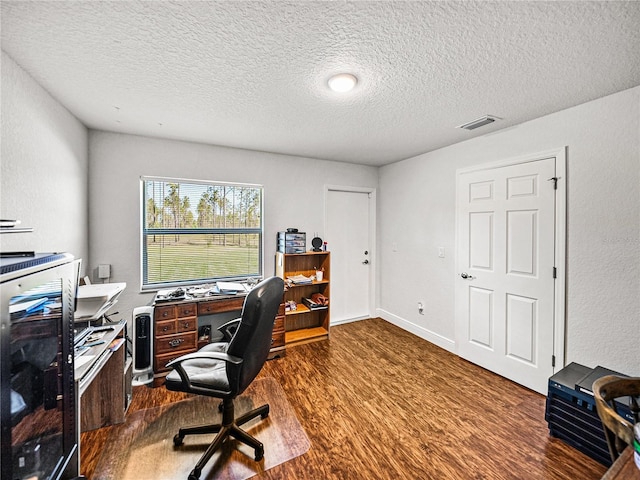 home office featuring visible vents, a textured ceiling, dark wood-type flooring, and baseboards