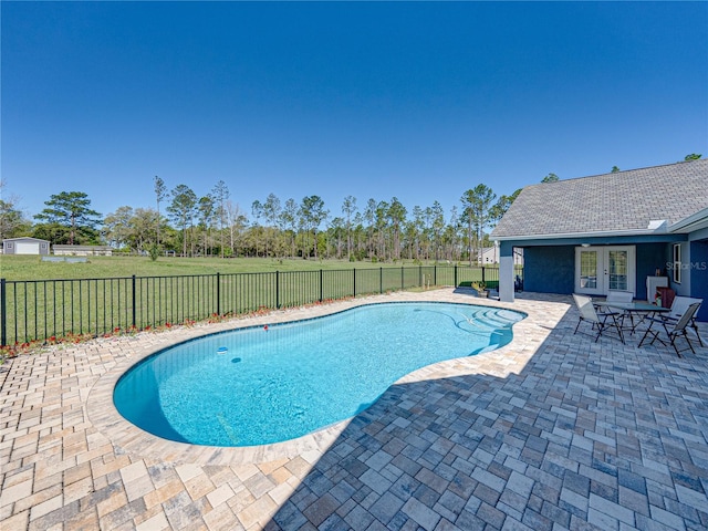 view of pool with a fenced backyard, french doors, a yard, a fenced in pool, and a patio area