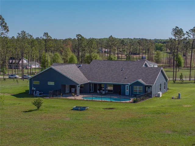 back of house with a shingled roof, a lawn, cooling unit, a patio area, and an outdoor pool