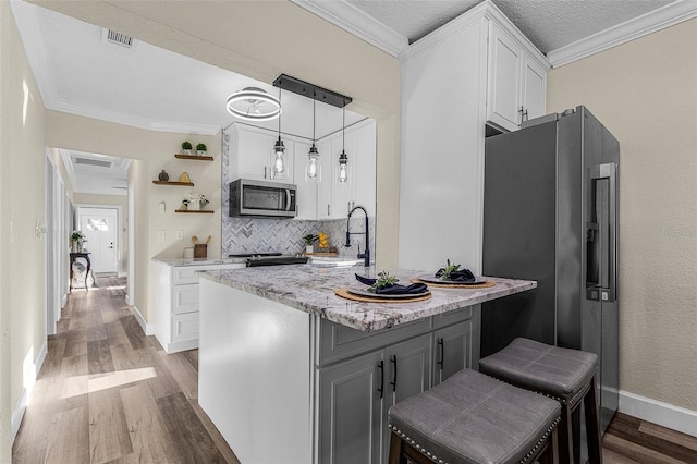 kitchen featuring a sink, stainless steel appliances, ornamental molding, and white cabinets