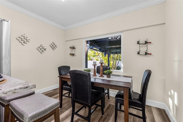 dining area with crown molding, wood finished floors, and baseboards