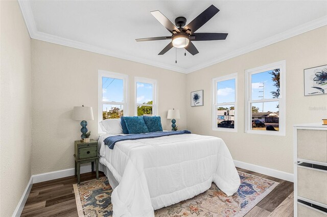 bedroom featuring baseboards, wood finished floors, and crown molding