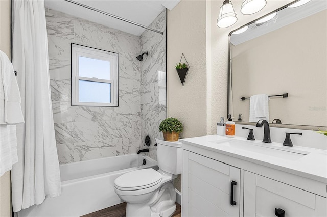 bathroom with vanity, toilet, a textured wall, and shower / bath combo