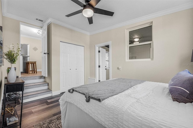 bedroom with visible vents, crown molding, dark wood-type flooring, ceiling fan, and a closet