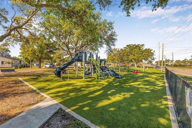 community jungle gym featuring a lawn and fence