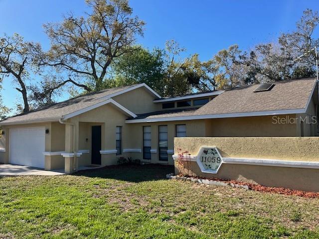 ranch-style home with stucco siding, driveway, a garage, and a front yard