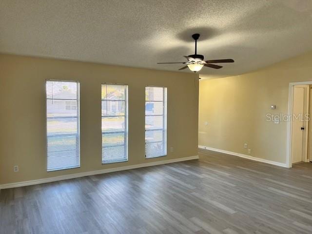 spare room featuring a textured ceiling, a ceiling fan, baseboards, and dark wood-style flooring