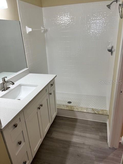 full bathroom with vanity, wood finished floors, and a tile shower