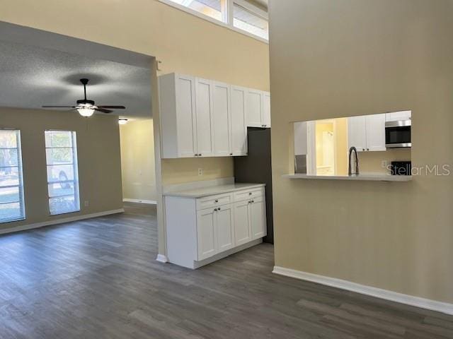 kitchen featuring stainless steel microwave, white cabinets, light countertops, and baseboards