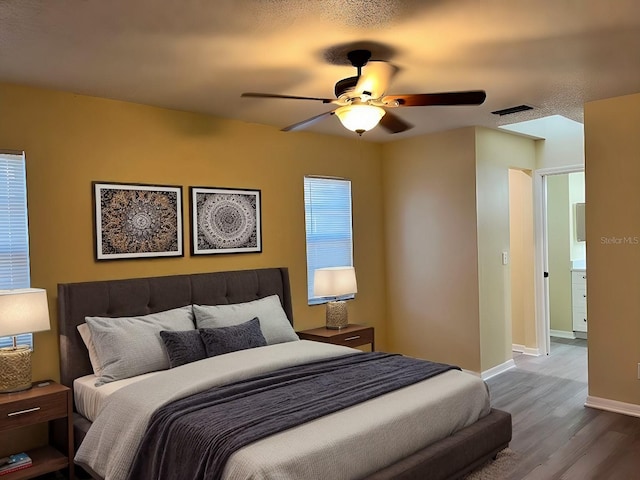 bedroom featuring ceiling fan, wood finished floors, visible vents, and baseboards