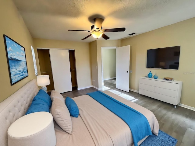 bedroom featuring wood finished floors, visible vents, baseboards, ceiling fan, and a closet