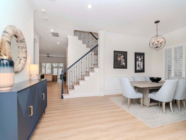 dining area featuring visible vents, light wood-style flooring, crown molding, and stairs