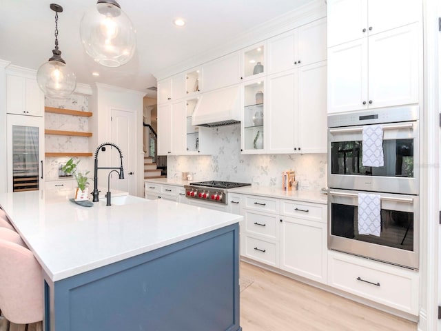 kitchen with custom range hood, open shelves, appliances with stainless steel finishes, light countertops, and decorative backsplash