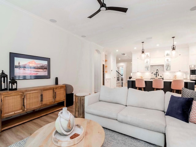 living room with ceiling fan, stairs, ornamental molding, recessed lighting, and light wood-style flooring