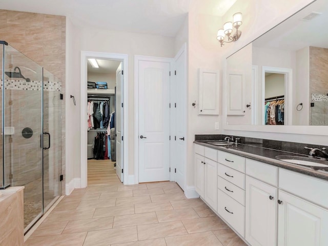 full bathroom with a shower stall, a spacious closet, double vanity, and a sink