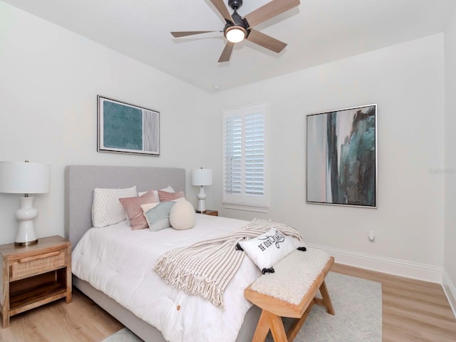 bedroom featuring baseboards, light wood finished floors, and ceiling fan