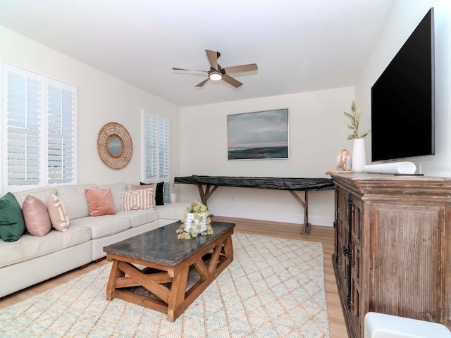 living room featuring baseboards, light wood-style floors, and ceiling fan