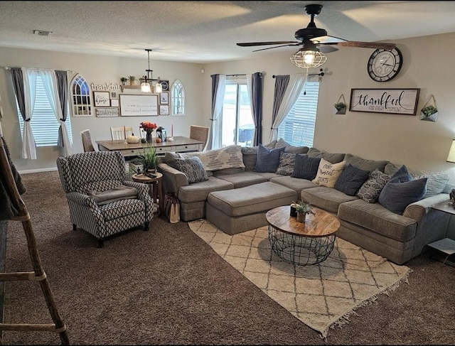 carpeted living area featuring visible vents, a textured ceiling, and ceiling fan with notable chandelier