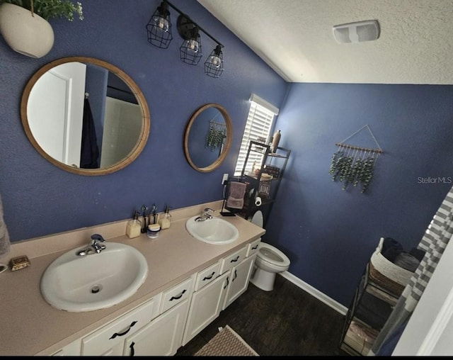 full bath featuring a sink, a textured ceiling, wood finished floors, and double vanity