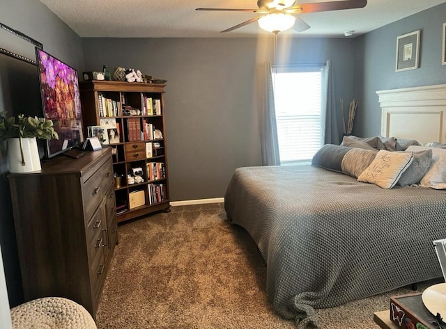 bedroom featuring a textured ceiling, baseboards, dark carpet, and ceiling fan