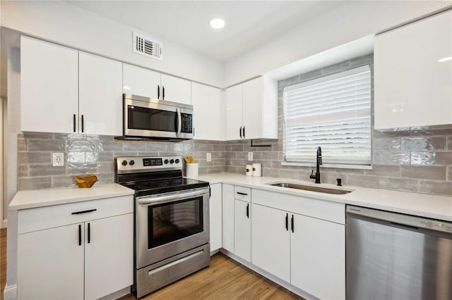 kitchen featuring visible vents, a sink, appliances with stainless steel finishes, white cabinetry, and backsplash