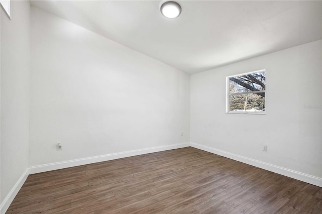 spare room with baseboards and wood finished floors