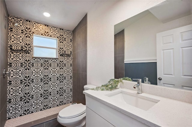 full bath featuring vanity, toilet, and a tile shower