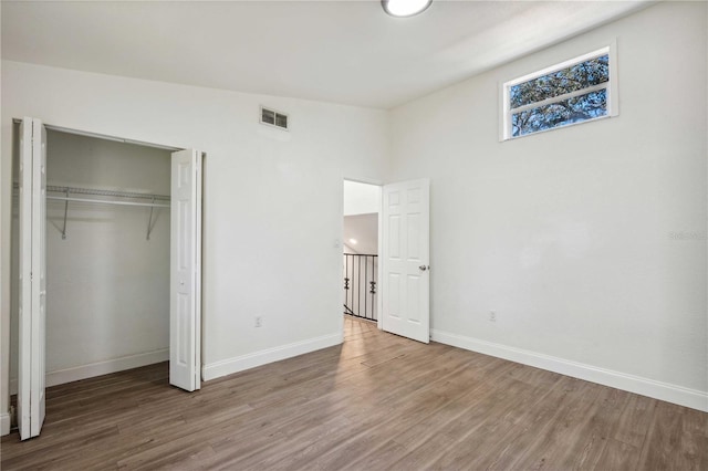 unfurnished bedroom with visible vents, baseboards, a closet, and wood finished floors