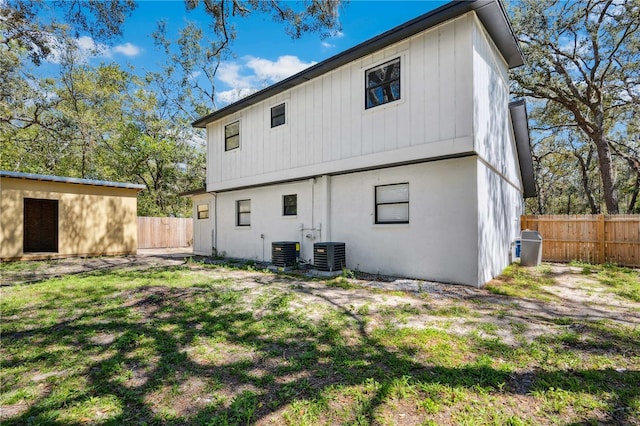 rear view of property featuring a yard, central AC unit, and fence