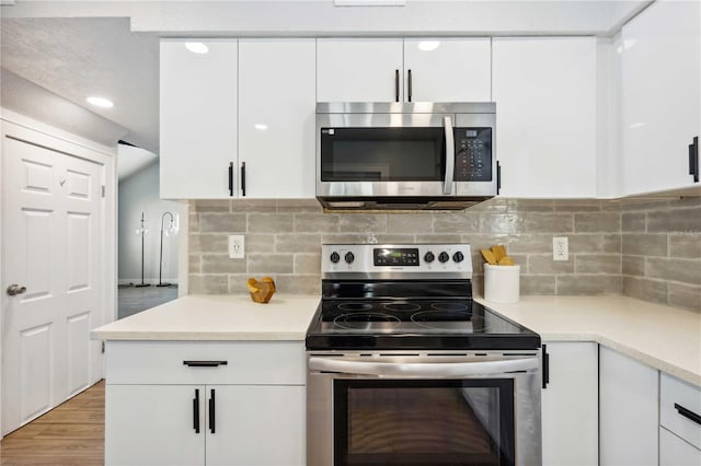 kitchen featuring backsplash, light wood-type flooring, light countertops, stainless steel appliances, and white cabinetry