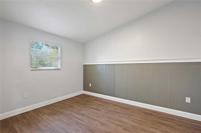 unfurnished room featuring baseboards, lofted ceiling, and wood finished floors