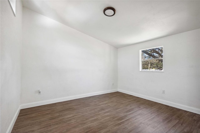 empty room featuring dark wood-style floors and baseboards