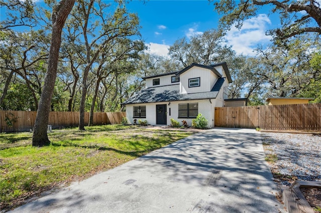 view of front of house featuring brick siding, driveway, and fence