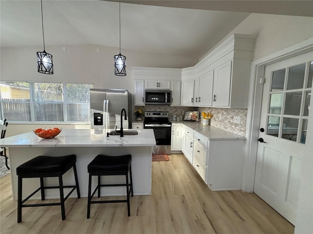 kitchen with tasteful backsplash, light wood-type flooring, vaulted ceiling, appliances with stainless steel finishes, and white cabinets