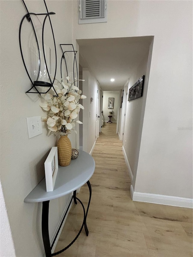 corridor featuring visible vents, baseboards, and light wood-style floors