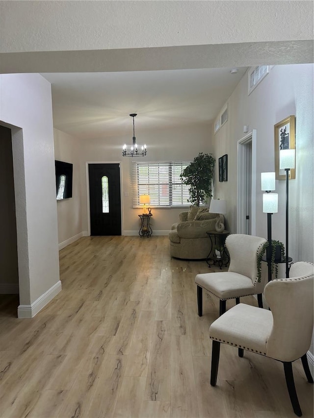 living room with light wood-style flooring, baseboards, visible vents, and a chandelier