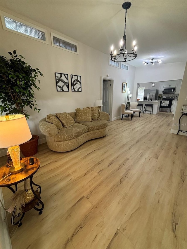 living area featuring a notable chandelier, visible vents, light wood-type flooring, and baseboards