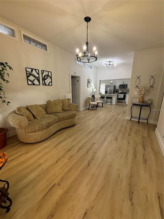 living room with a chandelier, visible vents, baseboards, and light wood-style floors