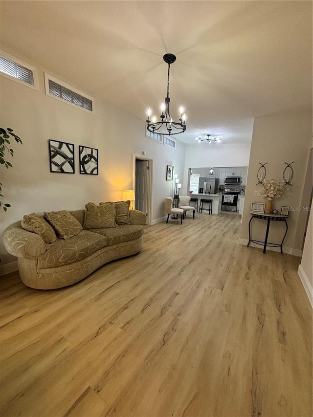 living area featuring visible vents, baseboards, an inviting chandelier, and light wood-style flooring