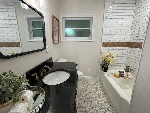 bathroom with a tub, baseboards, toilet, and vanity