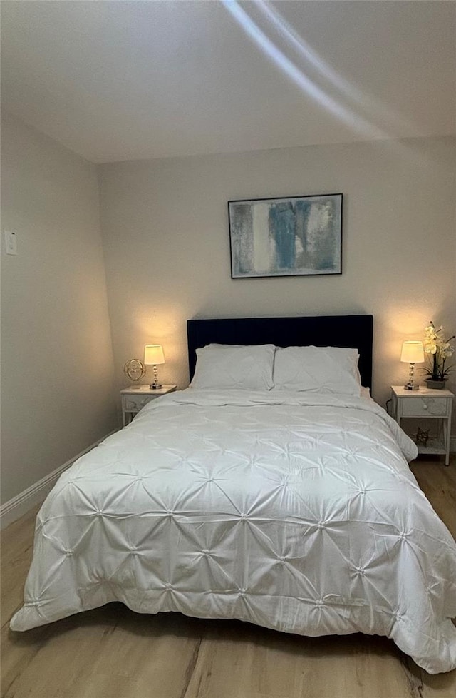 bedroom with wood finished floors and baseboards