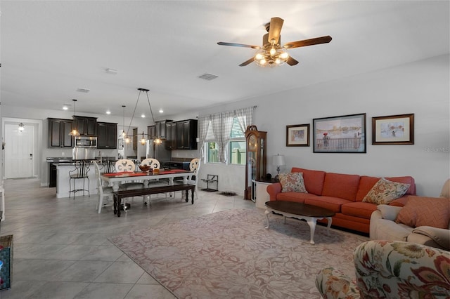 living room with light tile patterned flooring, visible vents, and a ceiling fan