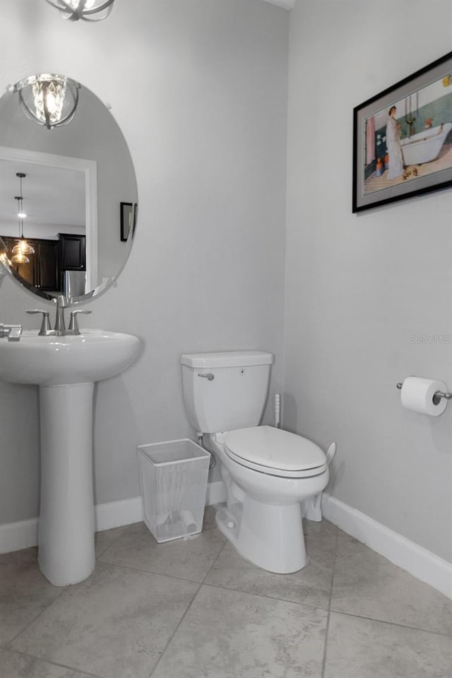 bathroom featuring toilet, baseboards, and a sink