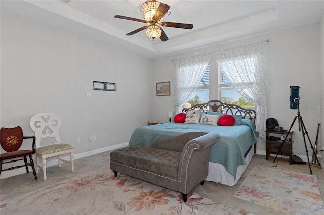 bedroom with ceiling fan, a raised ceiling, and baseboards