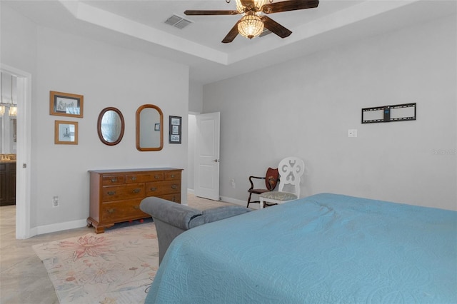 bedroom with a ceiling fan, a raised ceiling, baseboards, and visible vents