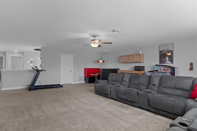 carpeted living room featuring visible vents, baseboards, a textured ceiling, and ceiling fan with notable chandelier