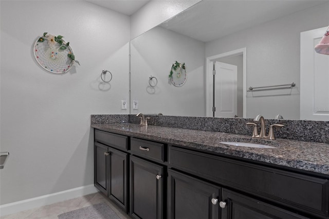 full bathroom with a sink, baseboards, double vanity, and tile patterned floors