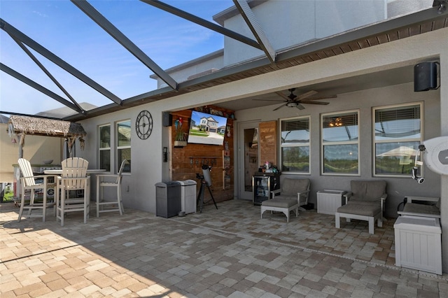 view of patio / terrace with glass enclosure, outdoor dining area, and ceiling fan