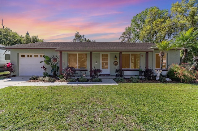 ranch-style home featuring a porch, stucco siding, an attached garage, and driveway