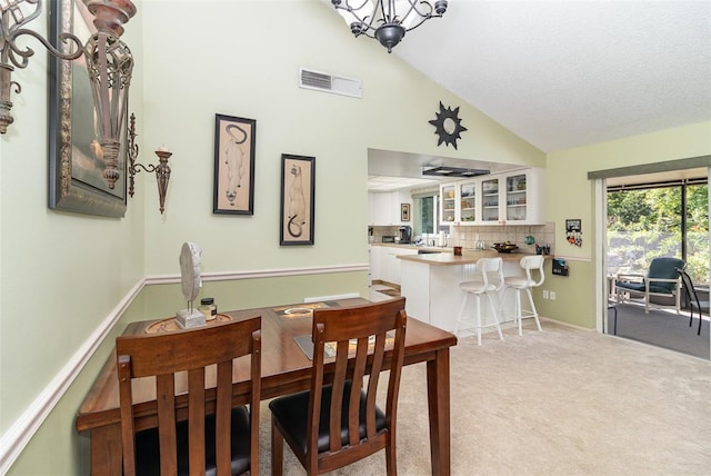 carpeted dining space with a chandelier, visible vents, baseboards, and vaulted ceiling